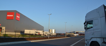 Penny Logistikzentrum. Graue Halle mit Penny-Logo drauf. Davor ein LKW.