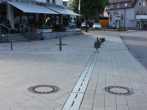 Innenstadt mit Ladenstraße. City Drain Rinne im Vordergrund auf der Straße verlegt.