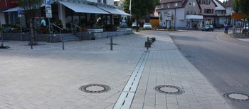 Innenstadt mit Ladenstraße. City Drain Rinne im Vordergrund auf der Straße verlegt.