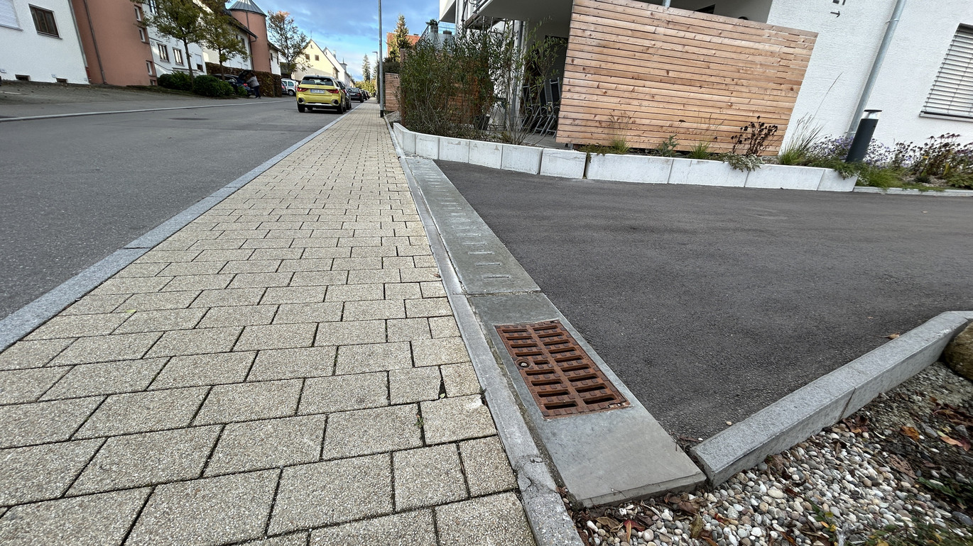 Wohnsiedlung. Area Drain Rinne verlegt zwischen Bürgersteig und Hauszufahrt.