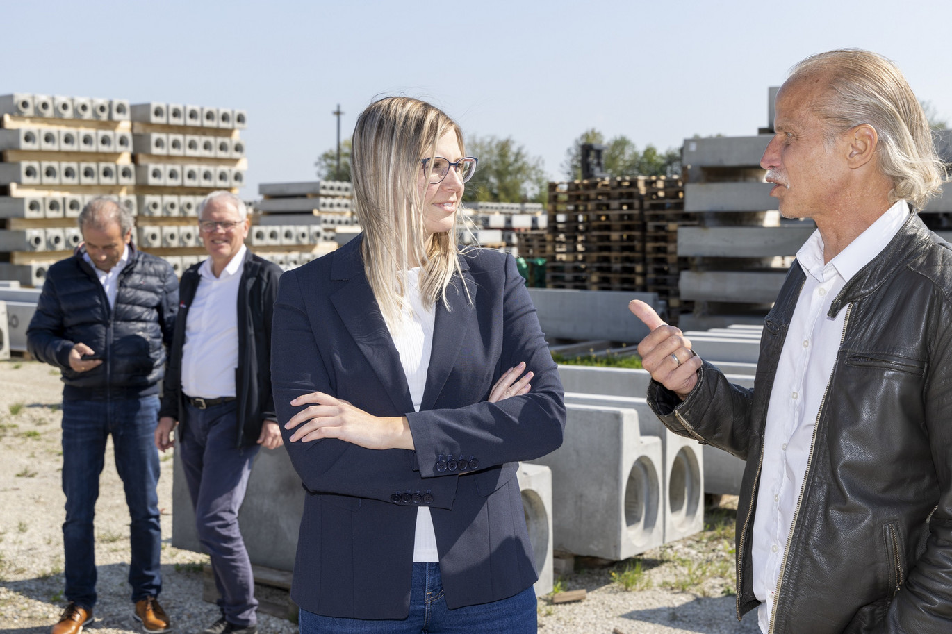 Mitarbeiter im Gespräch mit Kollegin. Im Hintergrund weitere Kollegen und Paletten mit Rinnen.