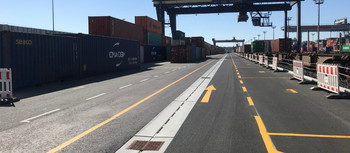 Pfuhler Rinne verlegt auf Containerhafen. Im Hintergrund viele Container und strahlend blauer Himmel.