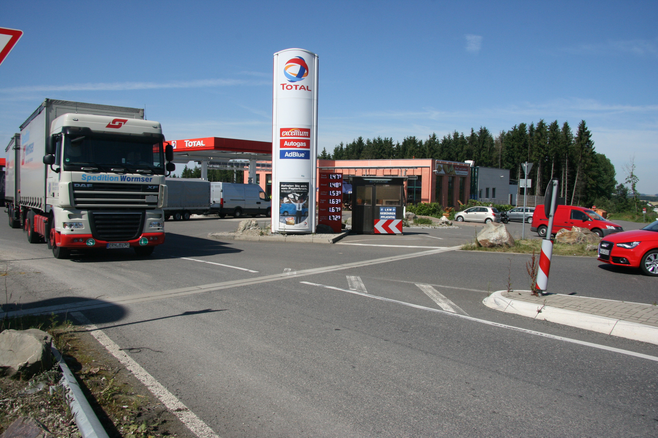 Tankstelle umgeben von LKW und Autos bei Sonnenschein